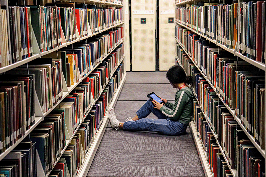 A girl reading in the book stacks.