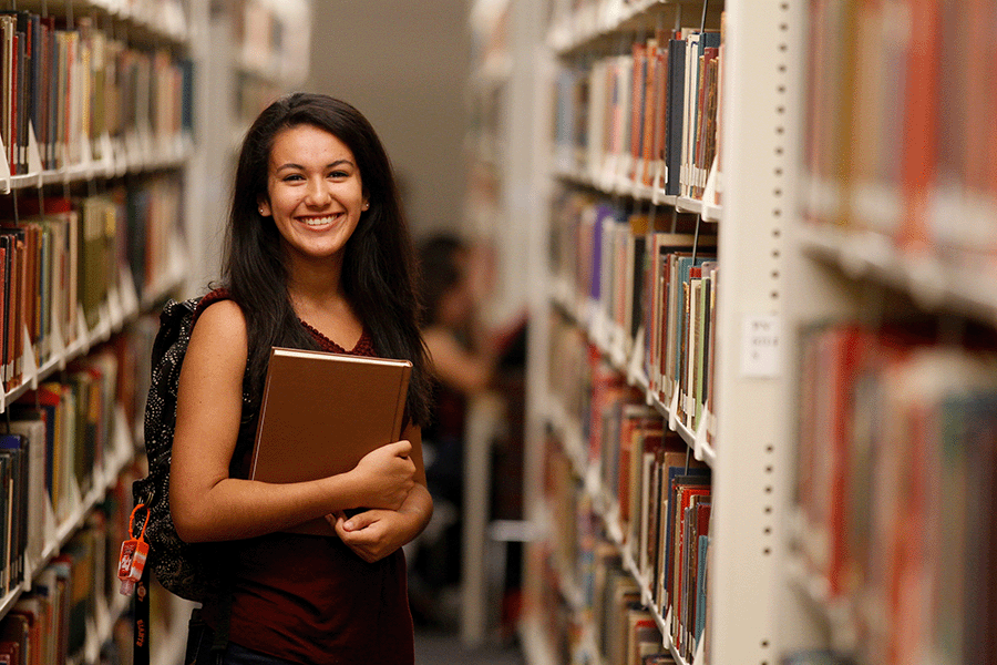 A female student standing in the book stacks.