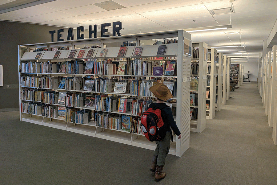 A child approaching some book stacks.